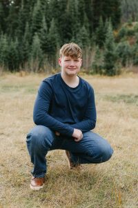 Smiling teenage boy crouching outdoors